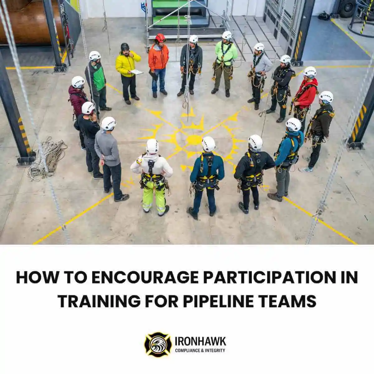 A collection of workers wearing hard hats and other PPE gathered in a circle for a meeting inside an industrial space.